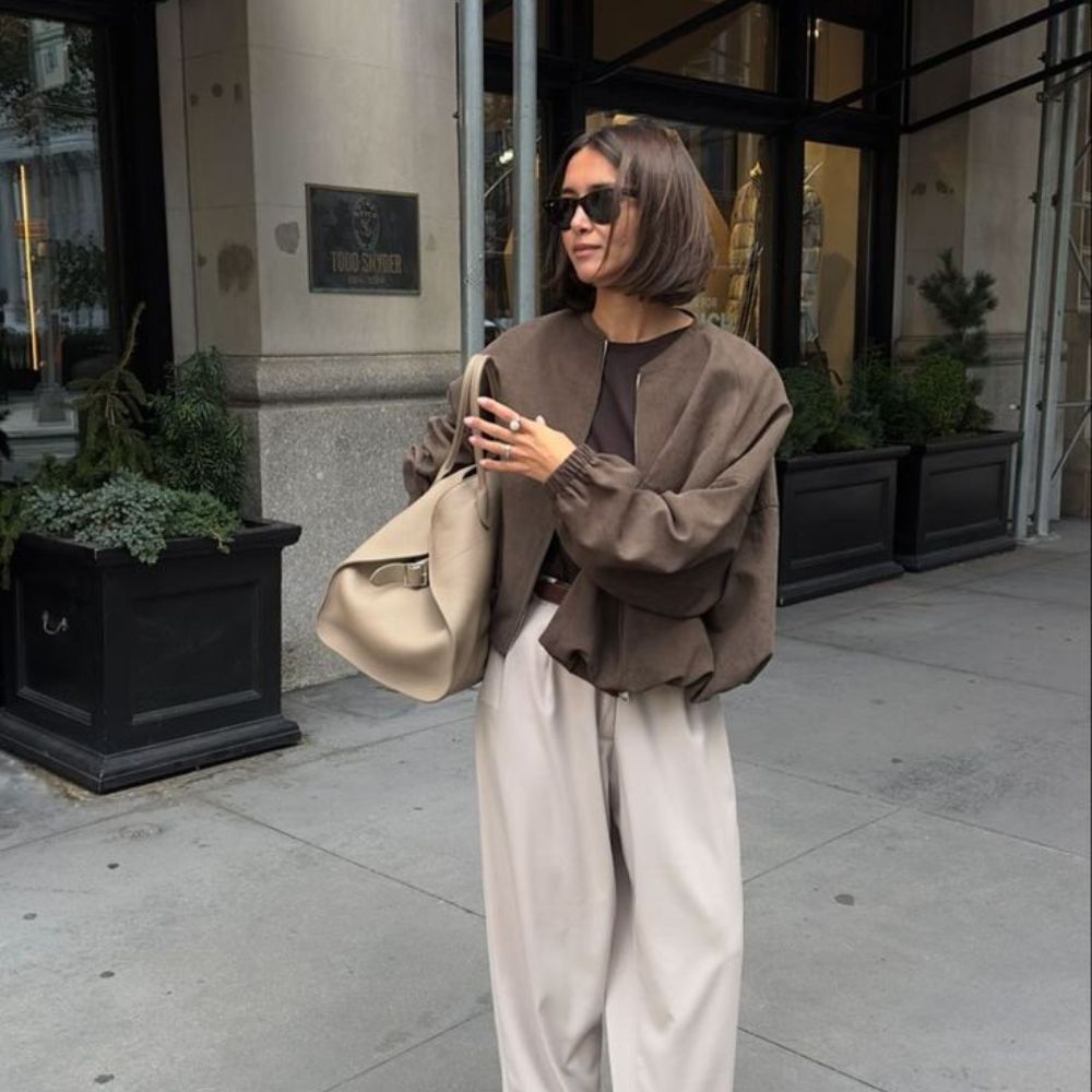 woman wearing a polished casual outfit featuring taupe trousers, a brown fitted tank and a brown bomber jacket