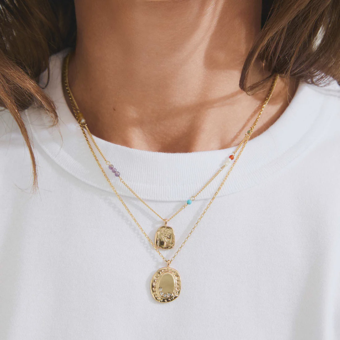 Gold necklaces with pendants on a white shirt