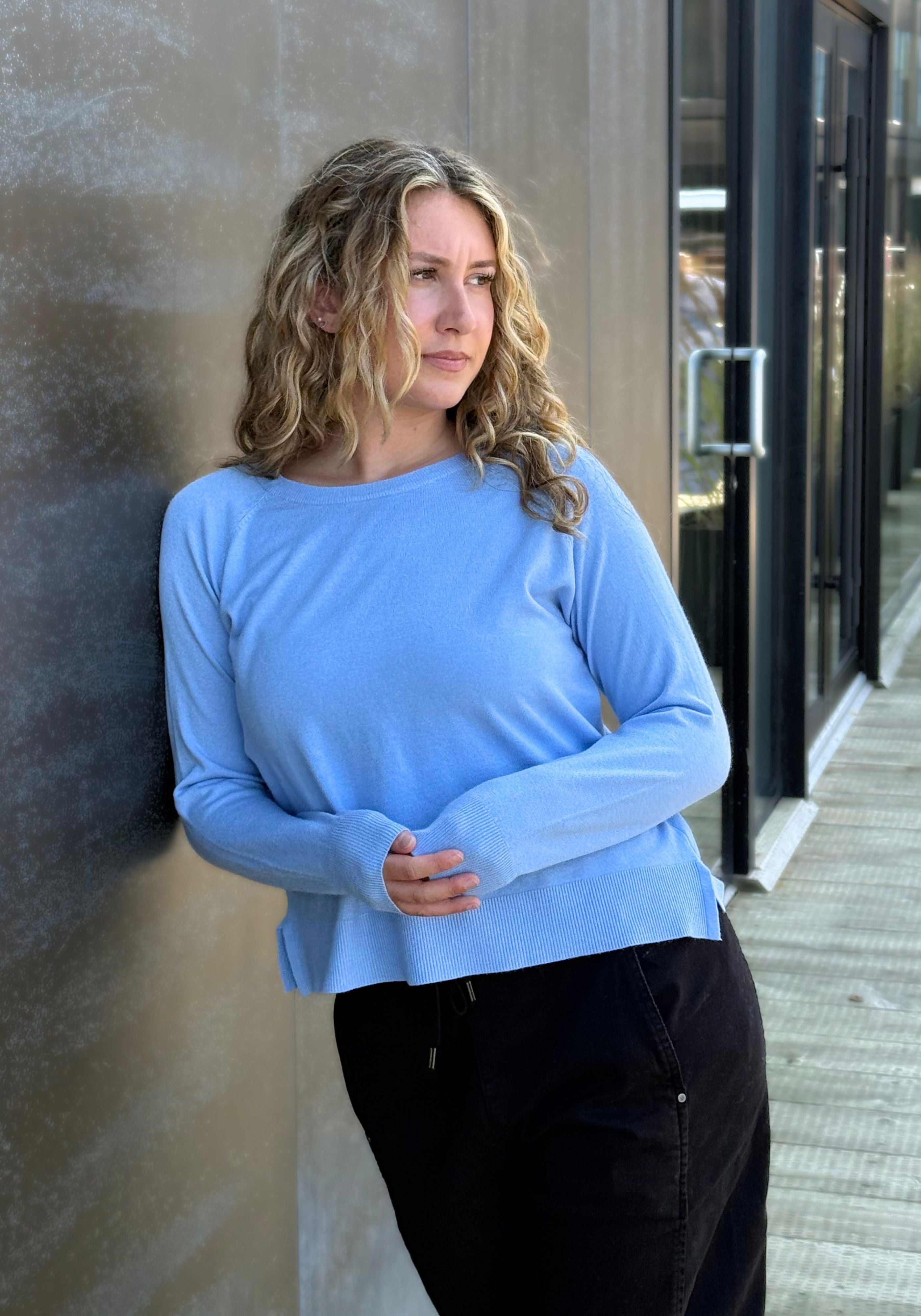 A woman wearing a light blue long-sleeve top and black pants.