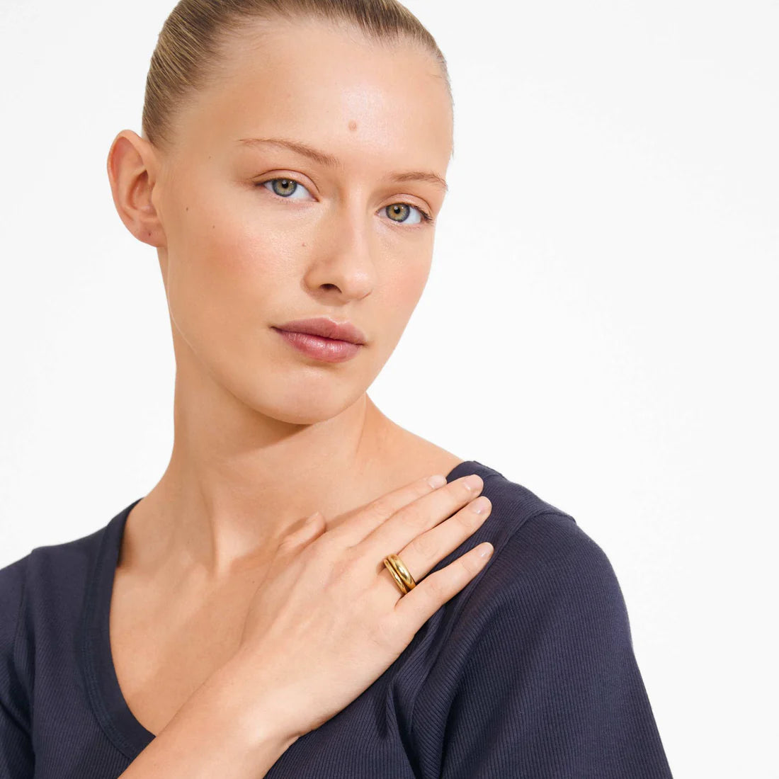 Woman wearing a gold ring on a plain background