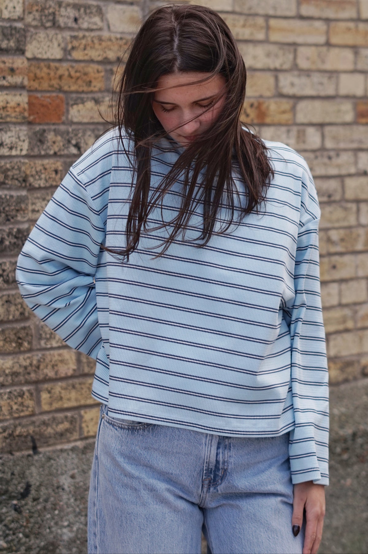 A woman wearing a light blue and white striped long-sleeve top and light wash jeans
