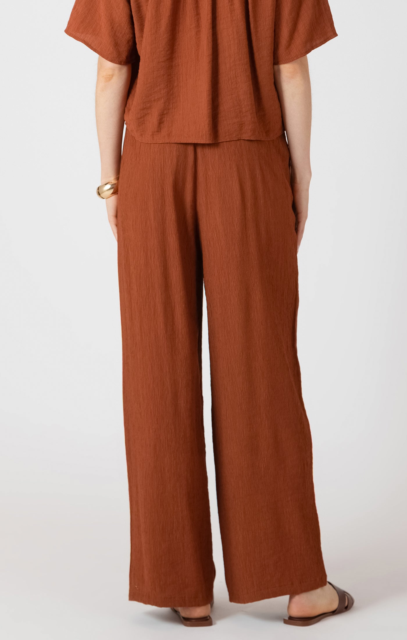 terracotta casual pants women, relaxed vacation pants women, effortless summer outfit women, warm neutral trousers women, wide leg drawstring pants outfit, rust colored trousers women
