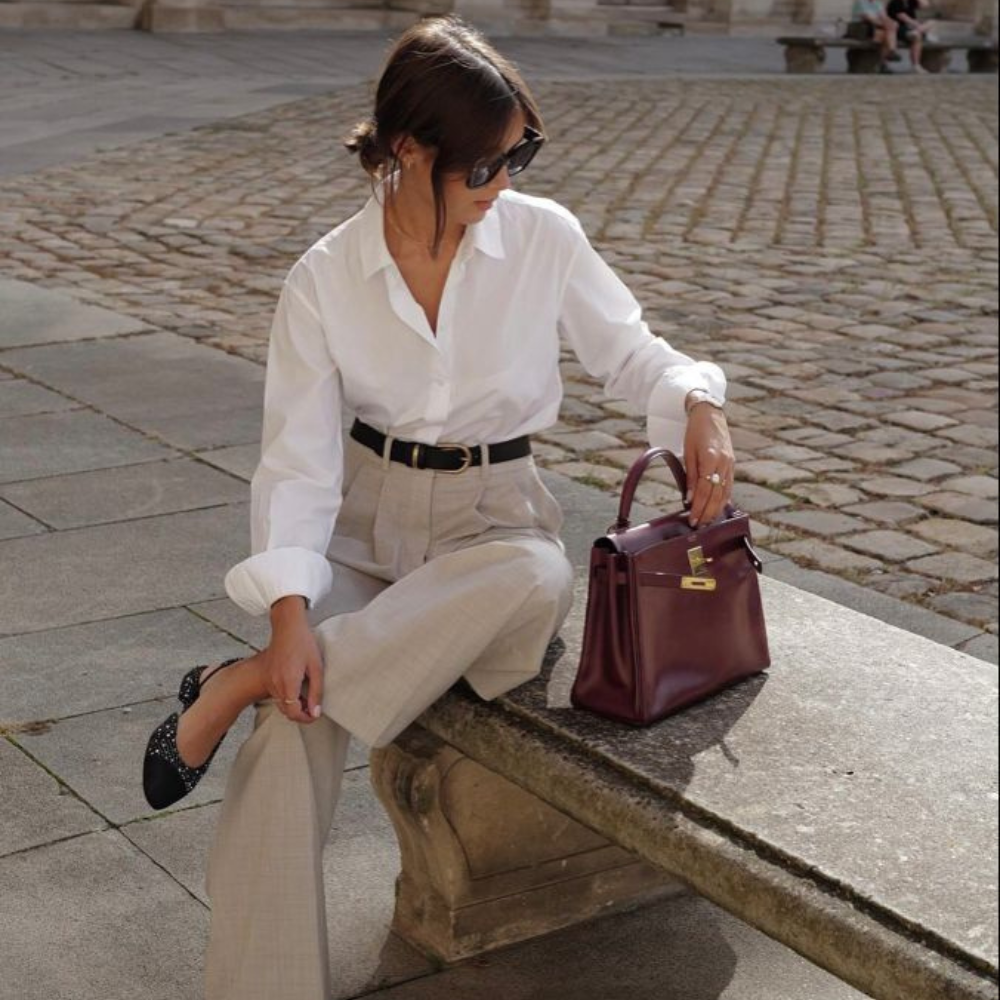 40 year old woman wearing button down shirt and cream pants in an off duty style edit.
