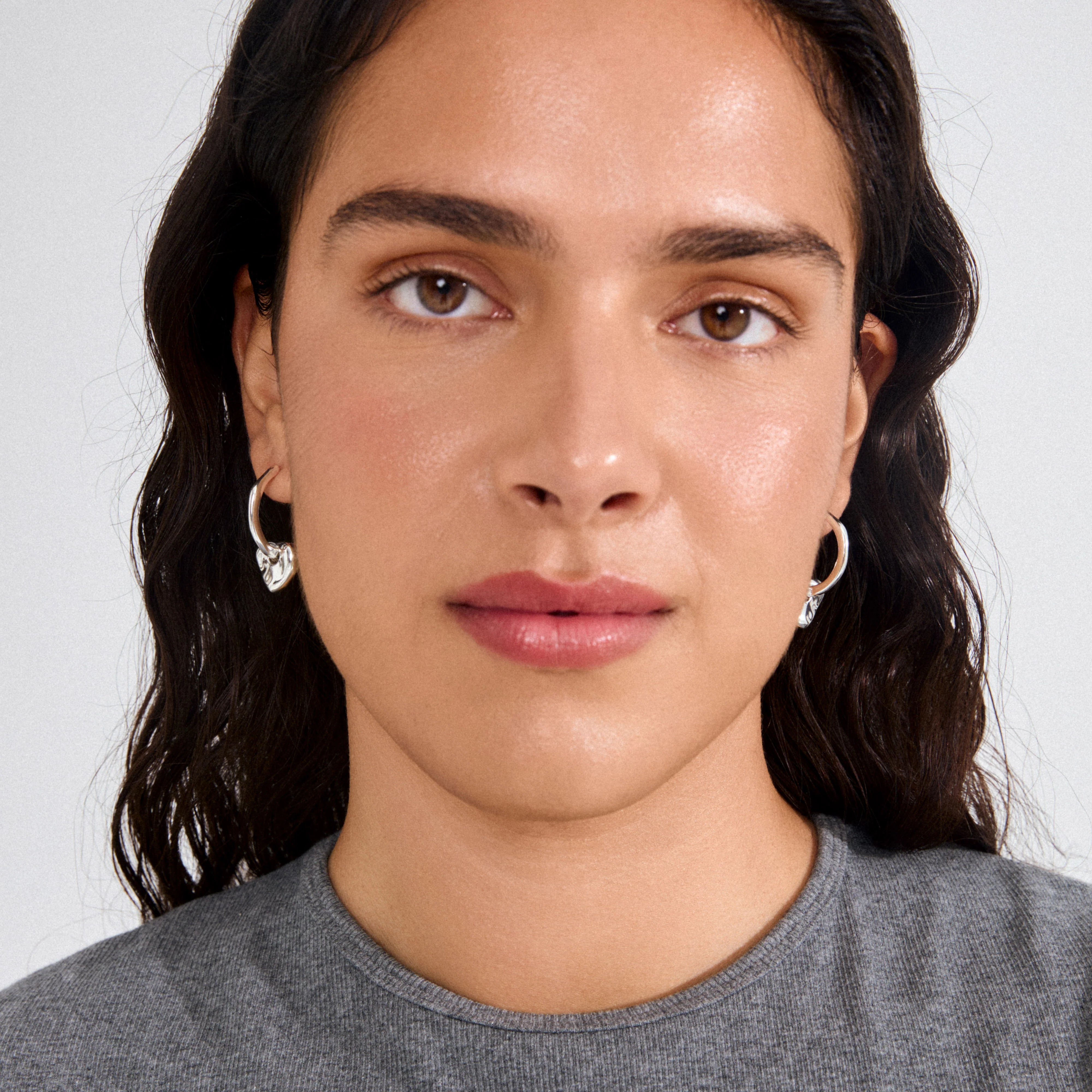 silver heart charm earrings, everyday hoop earrings, modern silver earrings, silver plated jewelry, stylish silver hoops, fashion earrings for women, minimalist statement earring