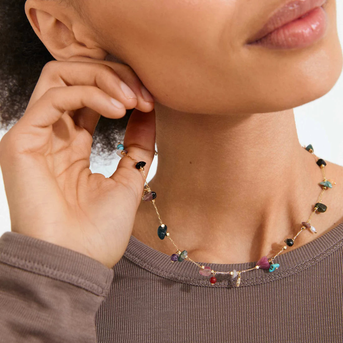 Close-up of a person wearing a colorful beaded necklace with a neutral background