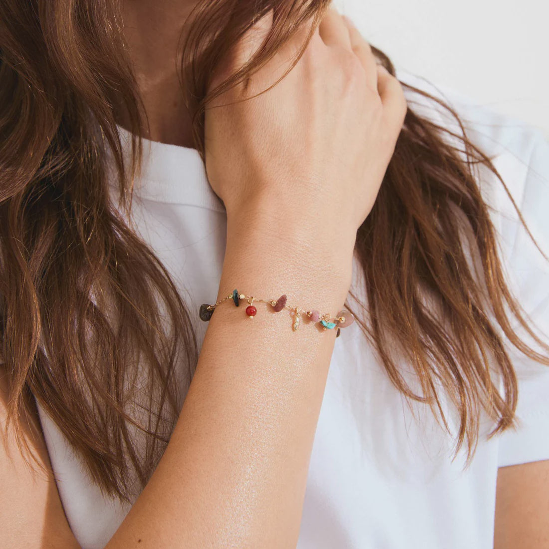 Close-up of a person wearing a bracelet with colorful beads on a plain background