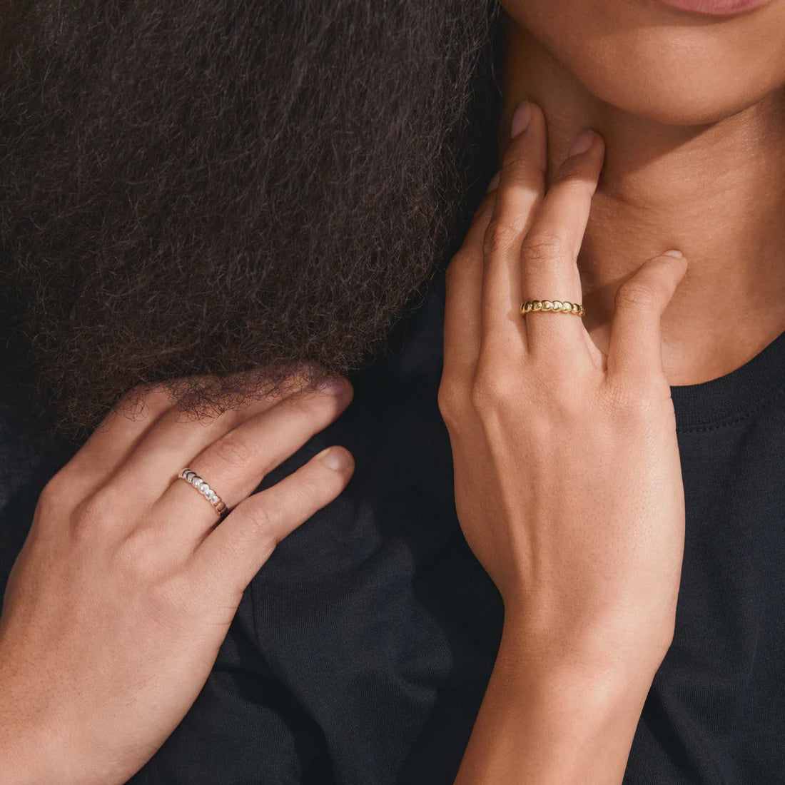 Close-up of two hands with rings on a dark background