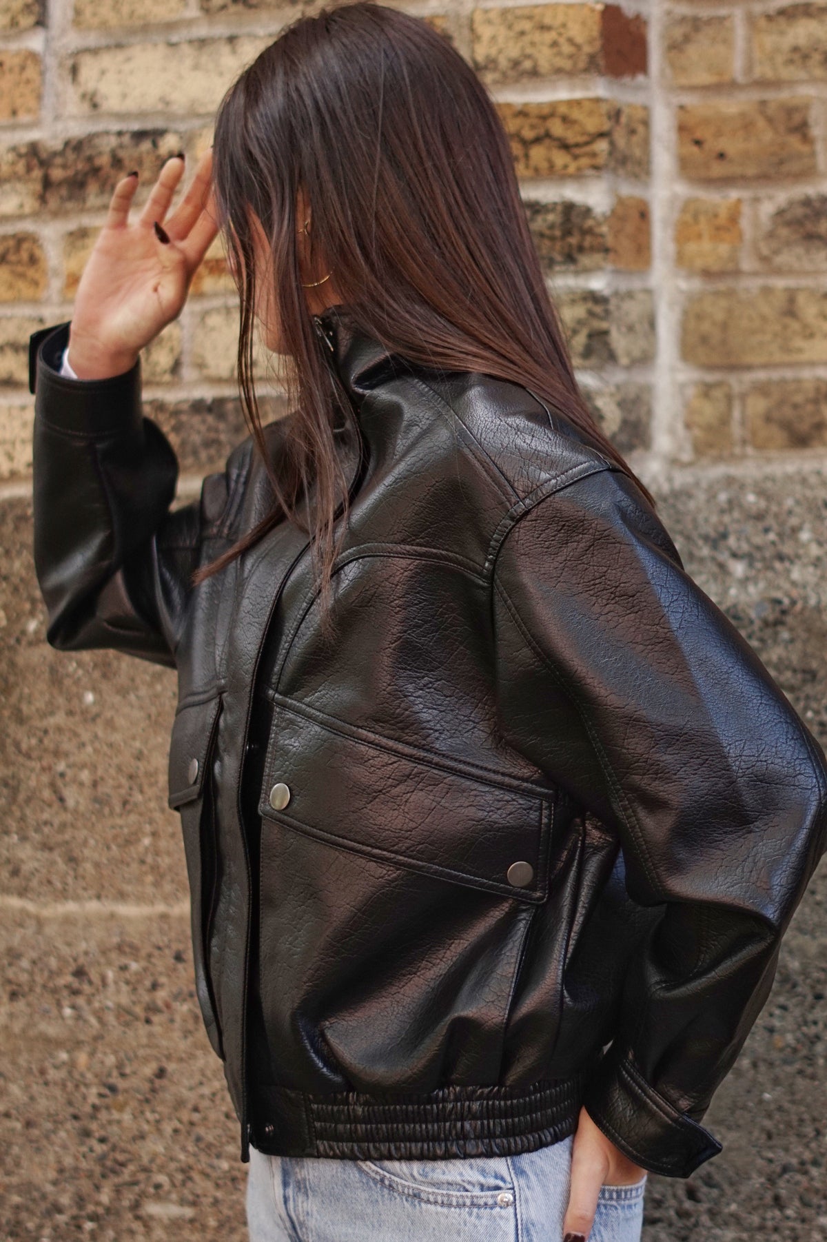 A woman wearing a black leather jacket and light blue jeans