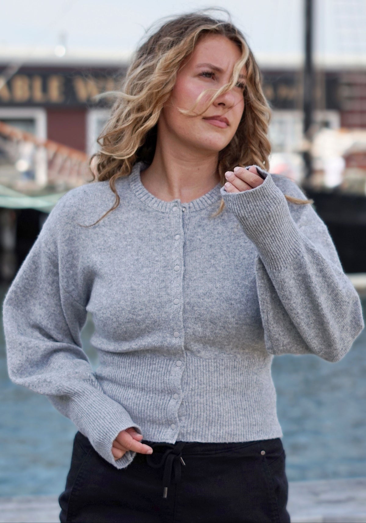 A woman wearing a light gray ribbed knit cardigan sweater with a button-up front.