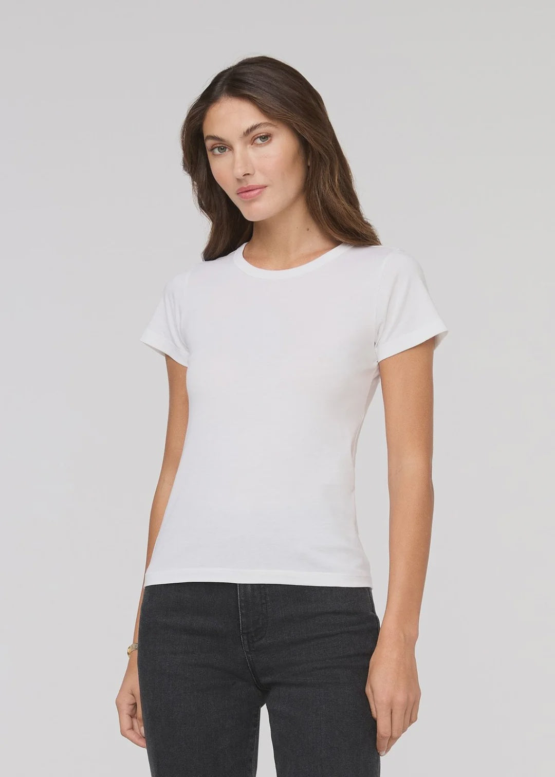Woman wearing a white t-shirt and black pants on a light gray background