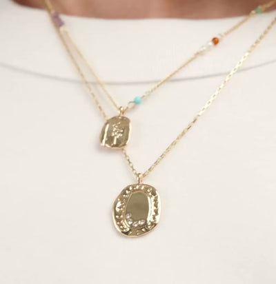 Gold necklaces with pendants on a white shirt