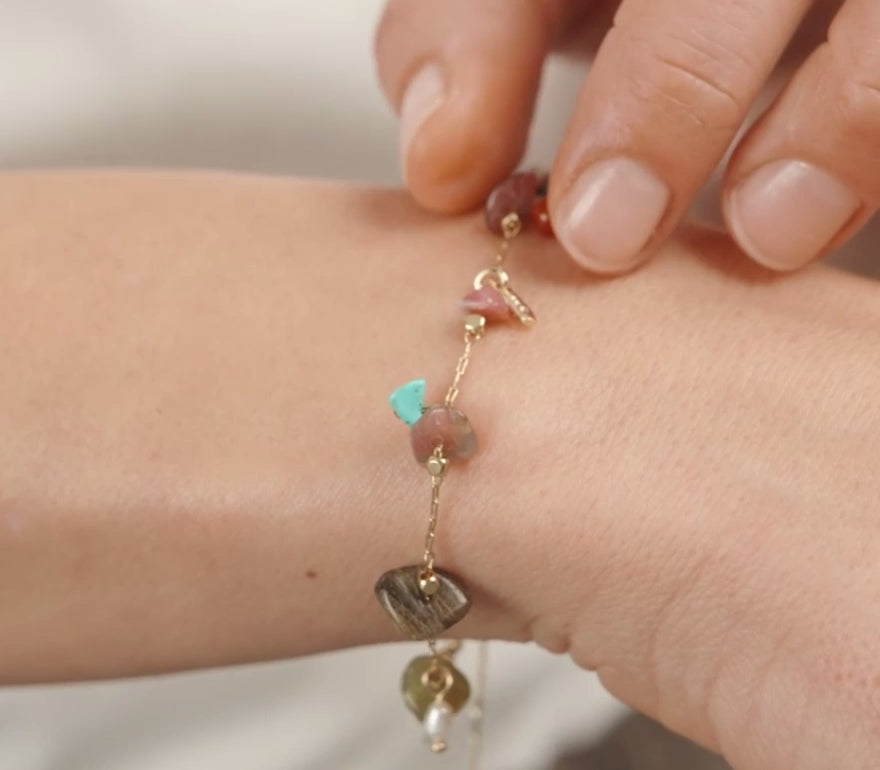 Close-up of a person wearing a bracelet with colorful beads on a plain background