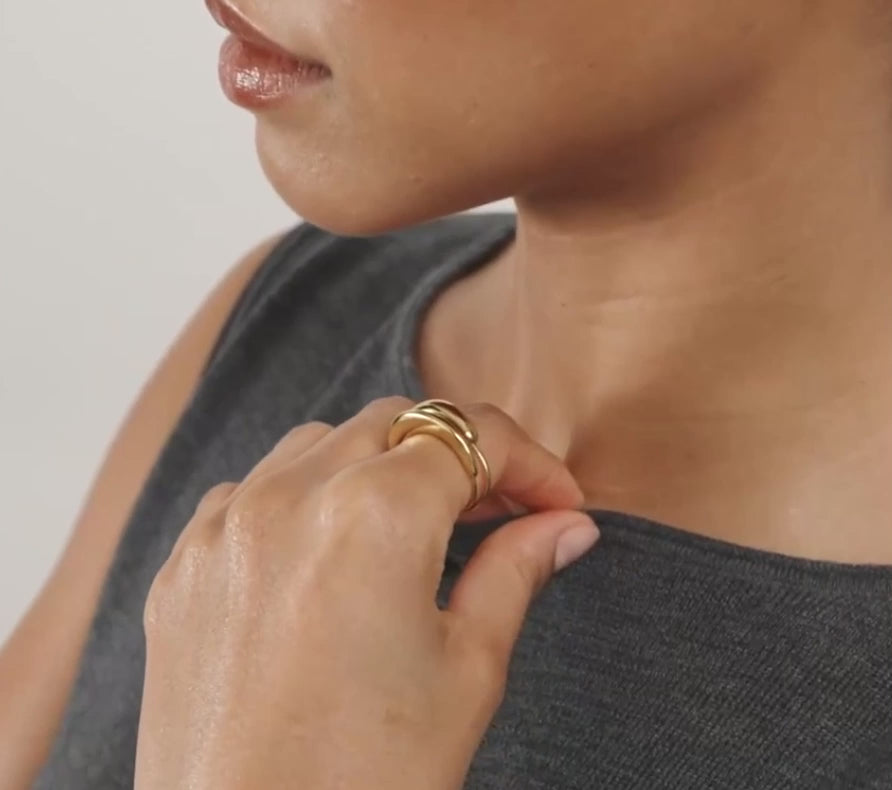 Close-up of a hand wearing a gold ring on a neutral background